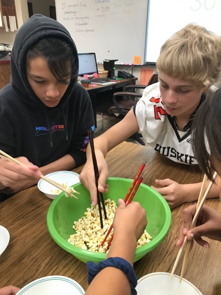 students pick up popcorn with chopsticks