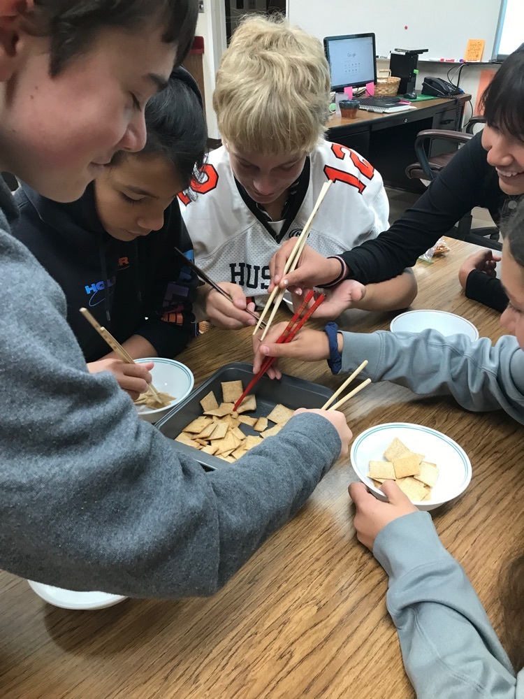 students pick up crackers with chopsticks