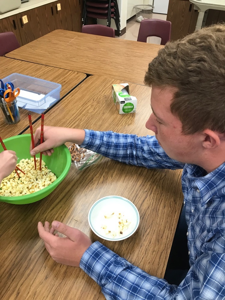 student picks up popcorn with chopsticks